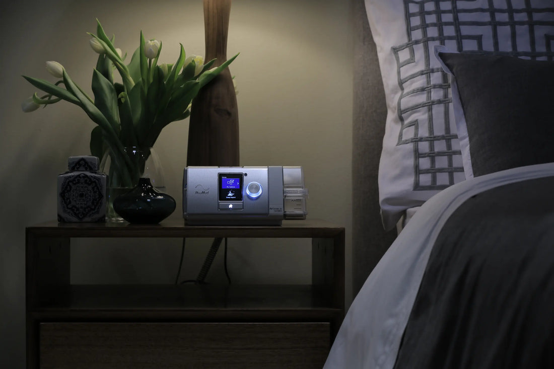 A CPAP machine on a nightstand next to a bed.