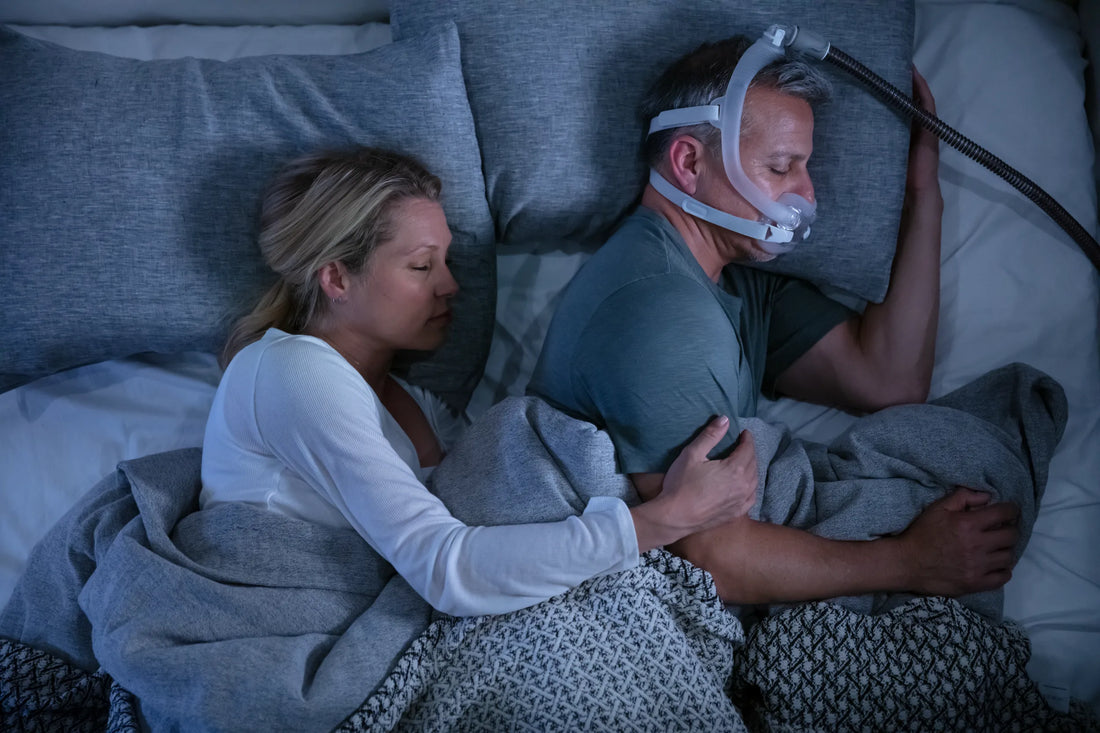 Couple sleeping together in bed using CPAP mask
