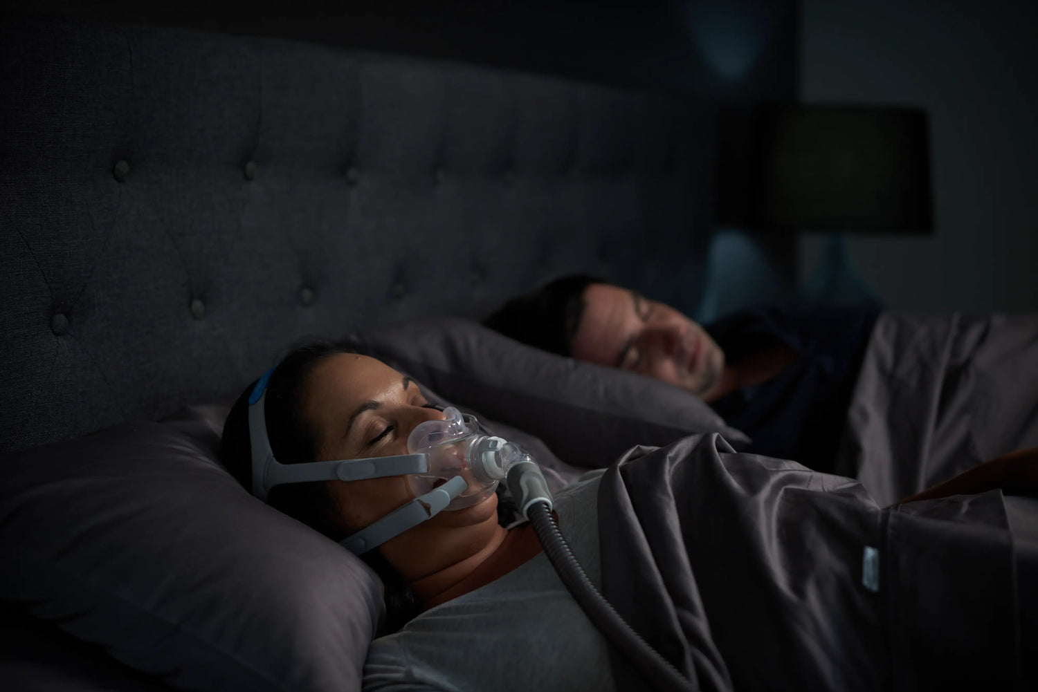 A female adult using machine while sleeping beside her partner