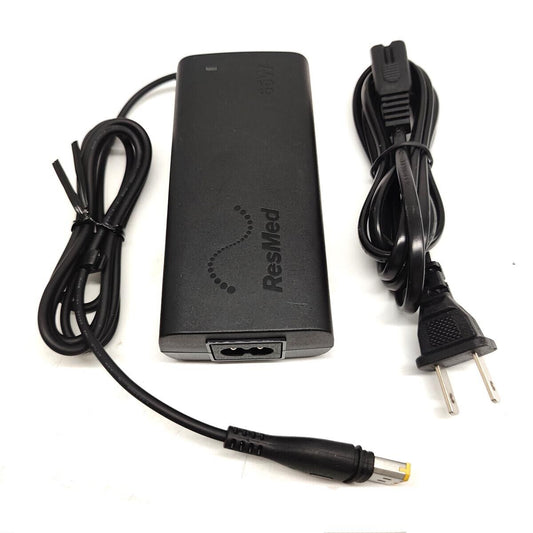 A black ResMed AirSense 11 power supply with a power cord and a two-prong plug.