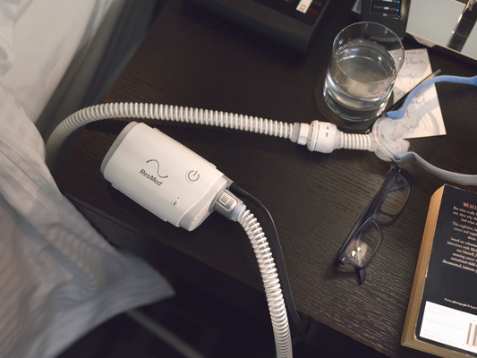 The ResMed AirMini AutoSet Travel CPAP Machine on a wooden bedside table