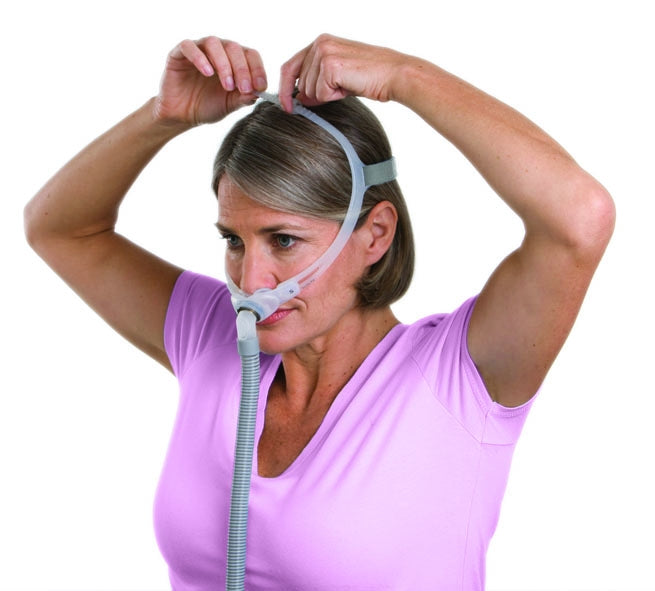 A woman fitting a Swift FX For Her Nasal Pillow CPAP Mask