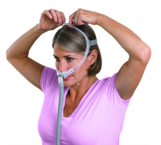 A woman fitting a Swift FX For Her Nasal Pillow CPAP Mask