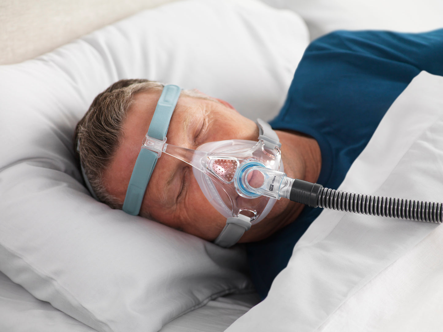 A man sleeping on the bed and wearing the Vitera Full Face CPAP Mask