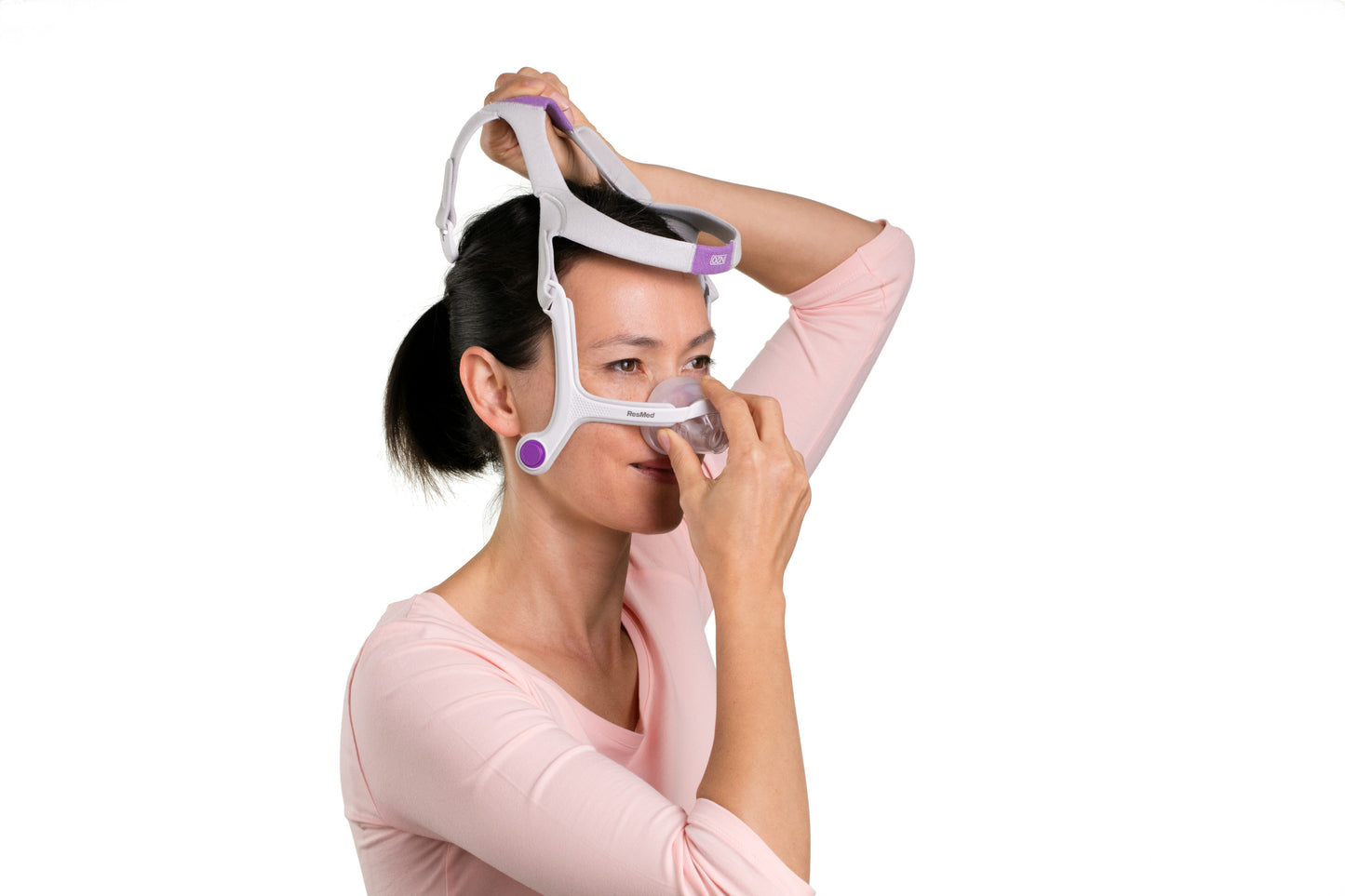 A woman putting on the AirFit N20 For Her Nasal CPAP Mask