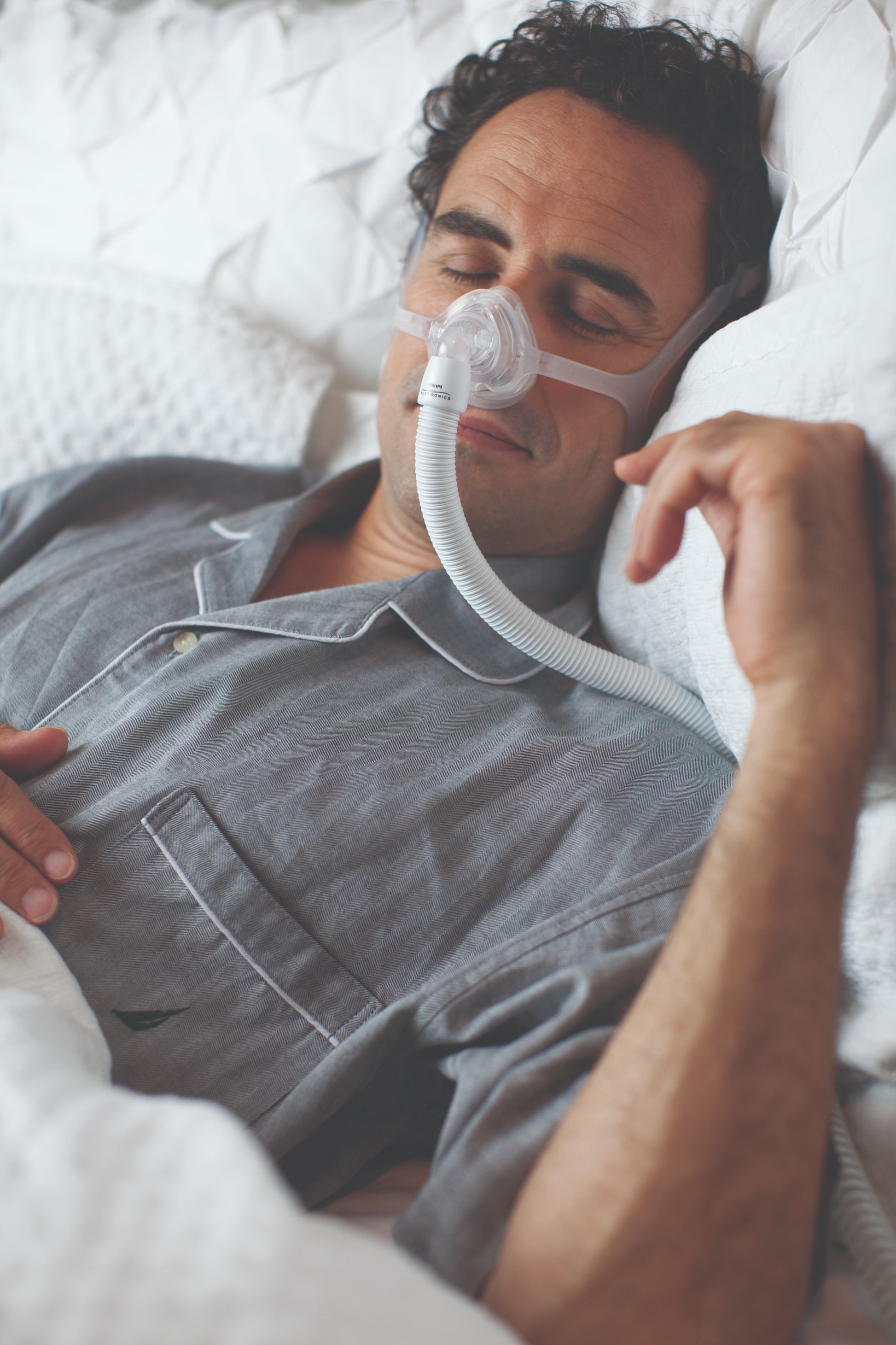 A man sleeping soundly wearing the Wisp Nasal CPAP Mask