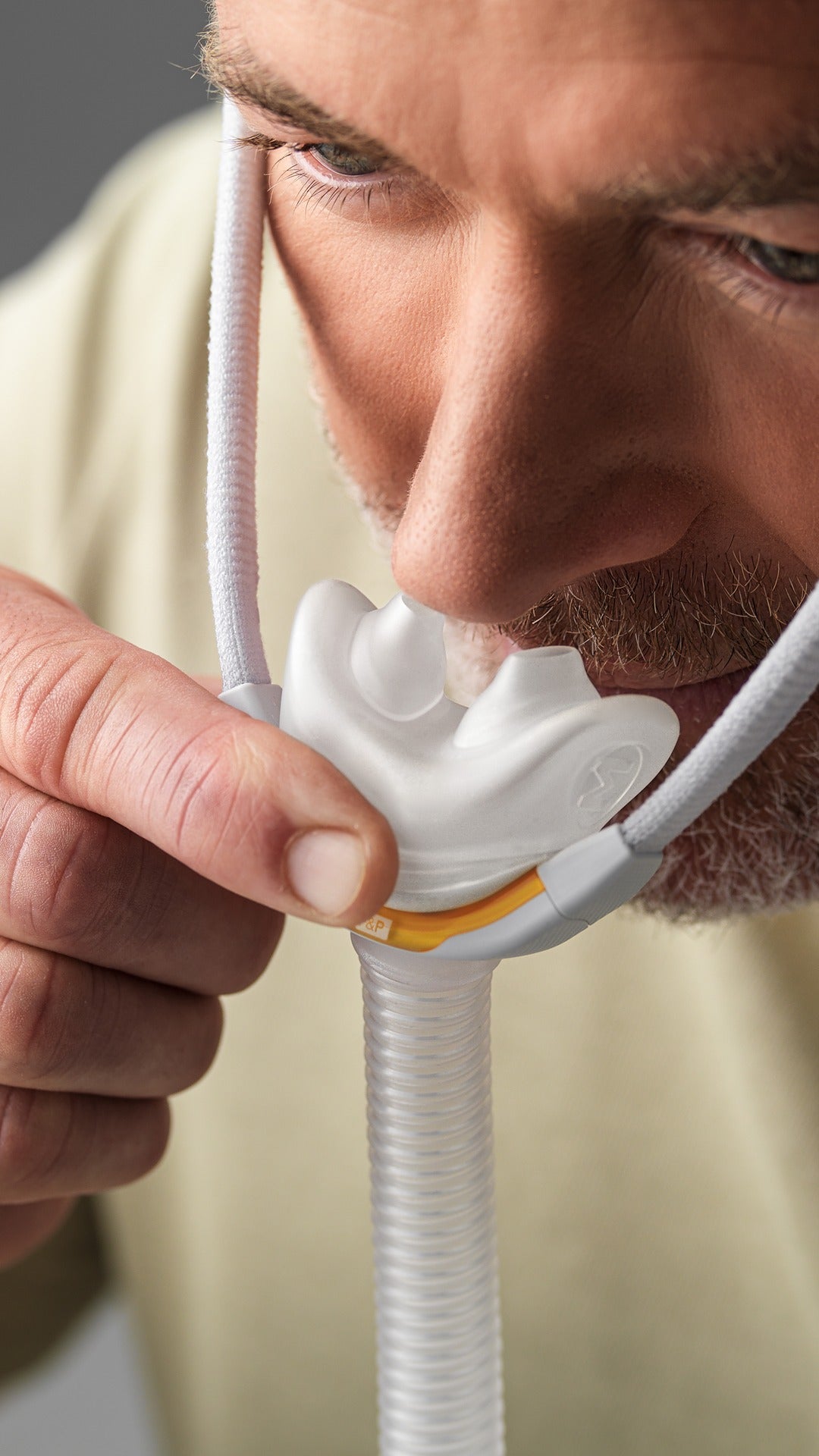 Man using the Fisher & Paykel Solo Nasal Pillow Mask with a gray background