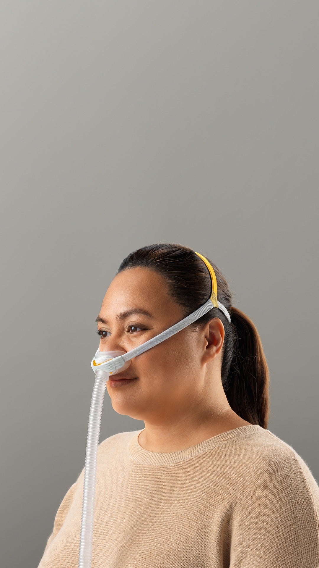 Woman wearing the Fisher & Paykel Solo Nasal Pillow Mask against a gray background