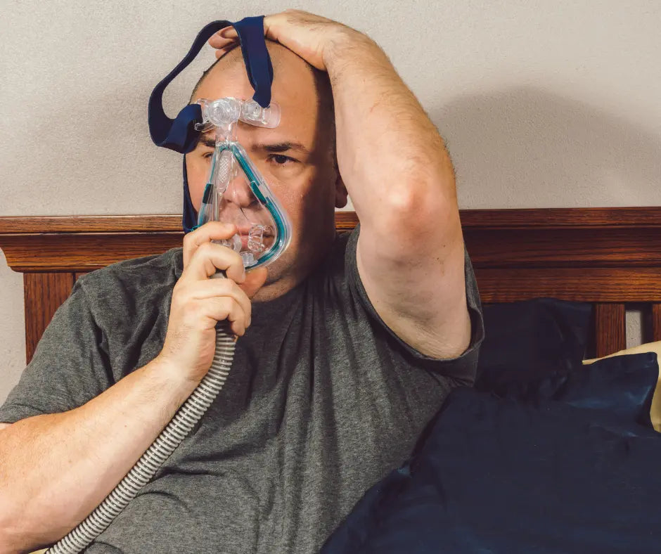 Man adjusting his CPAP mask in bed.