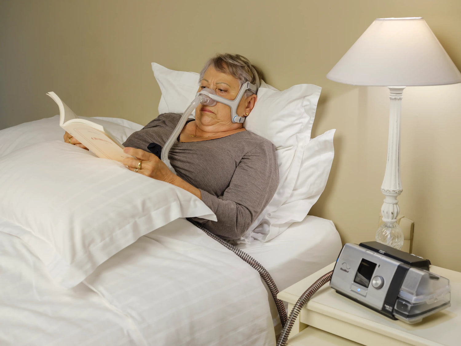 A female adult using a cpap machine while reading a book