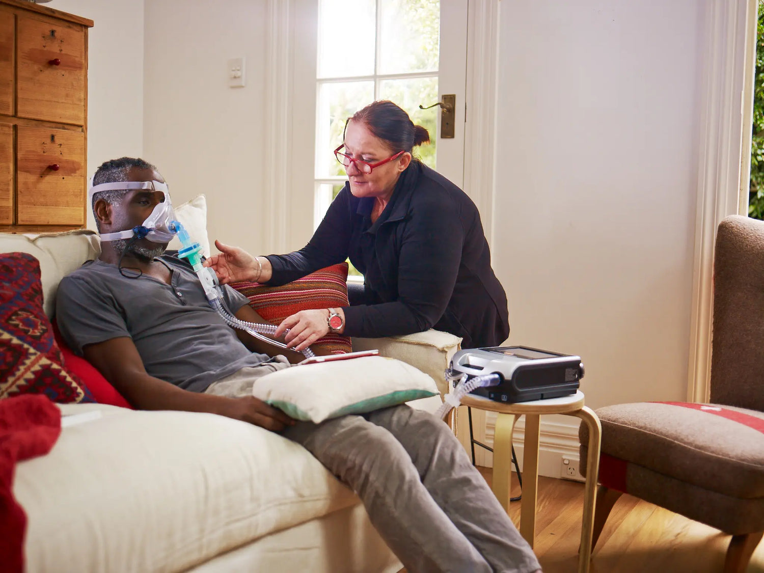 Man using cpap machine while women is assisting