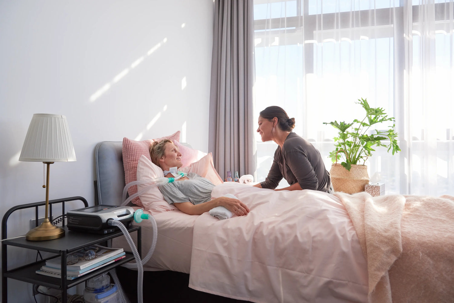 Woman lying in bed using her machine with her daughter watching over her