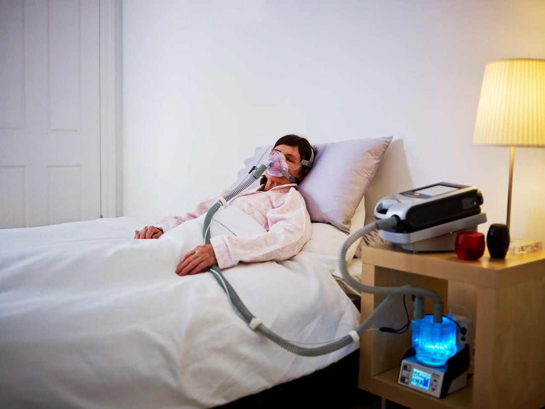 A woman in her bed sleeping while using her CPAP machine